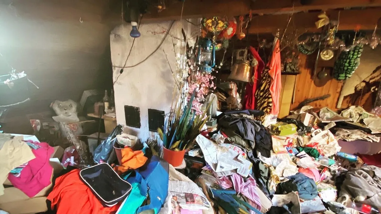Vollgestellter Dachboden vor dem gemauerten Kamin, Kleidung und Kisten bis zur Decke
