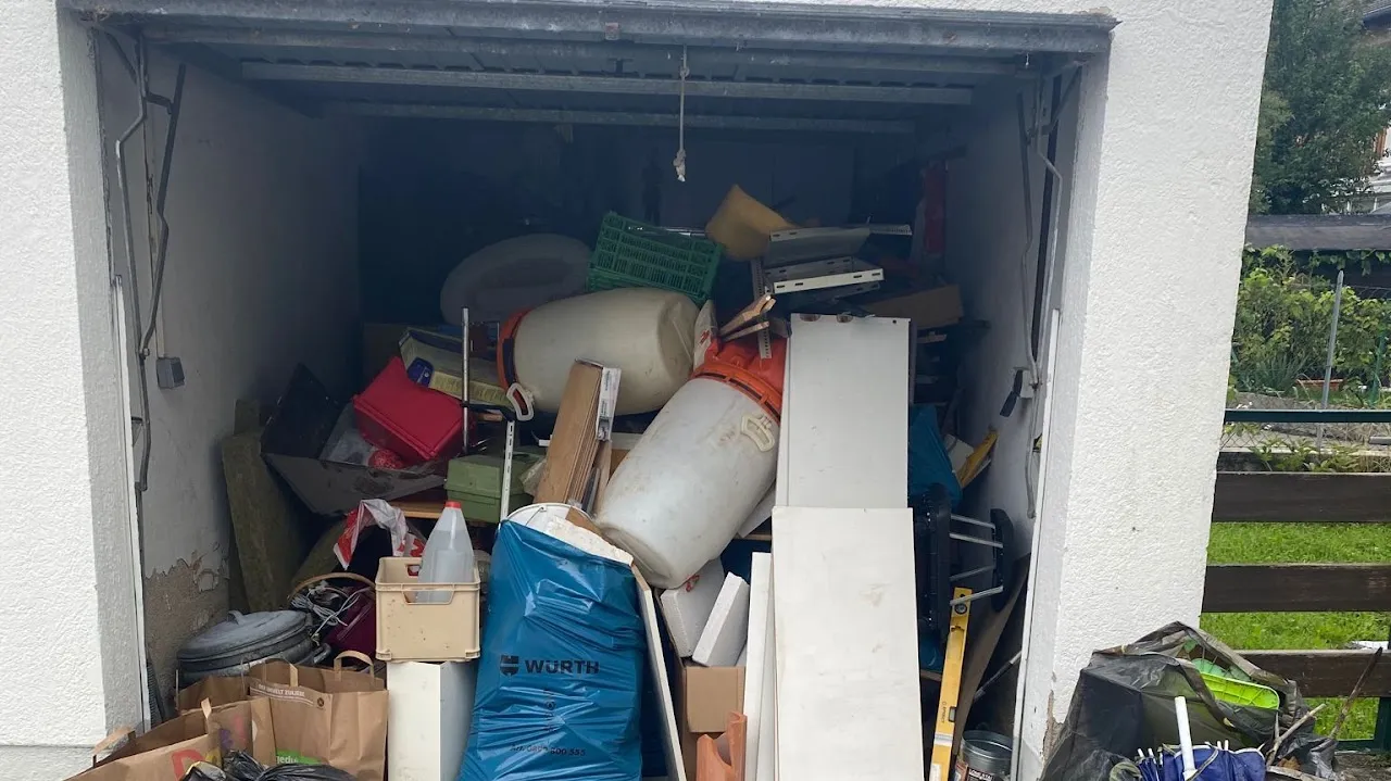 Garage bis unter das Tor vollgestellt mit Kisten, Kanistern und Brettern